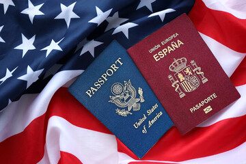Passport of Spain with US Passport on United States of America folded flag close up
