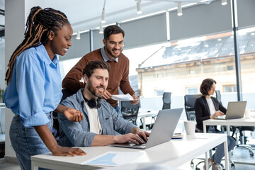 Team of diverse business professionals using laptop while working together