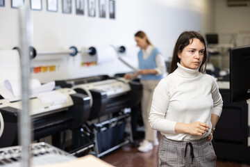 Printing office manager looking at display, controlling work of printing device.