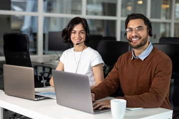 Fototapeta na wymiar Office employees in headset using laptop for work in coworking space