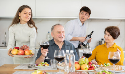 Father and mother together with adult children talking at the dinner table at home