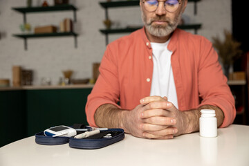Unrecognizable man sitting at table with diabetic equipment at home
