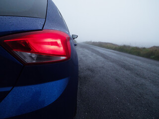 Side of a blue small car parked on a small country road with high quality asphalt surface on a...