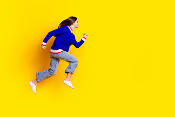 Full length photo of pretty teen girl jumping running fast wear trendy knitwear blue outfit isolated on yellow color background