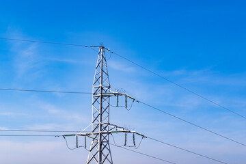 Energy infrastructure. High voltage electric transmission pylon, or tower, against blue sky. Close-up. Copy space.