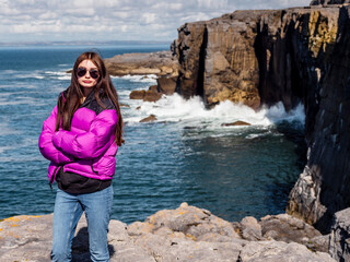 Teenager girl enjoys stunning view of mini cliffs in county Clare, Ireland. Warm sunny day. Travel...