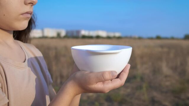 Fugitive child with no food. A view of fugitive little girl stand in the field with empty plate.