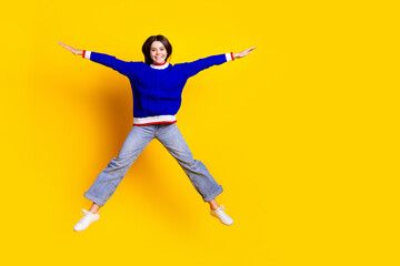 Fototapeta na wymiar Full length photo of pretty teen girl jumping spread hands legs wear trendy knitwear blue outfit isolated on yellow color background