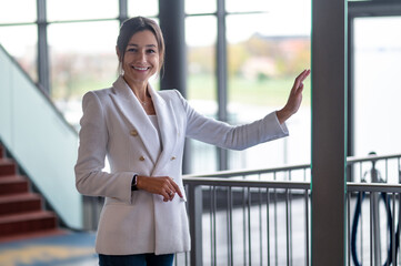 Pretty smiling business woman standing near the banister