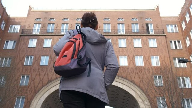 Woman with backpack against brick downtown. A female have a trip in Europe downtown with brick houses in the day light.