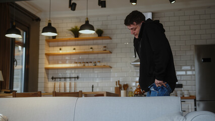 Man in a hurry to go to work, wearing jeans and talking on the phone, hurriedly gets ready for work.