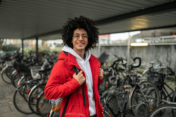 Smiling curly-haired guy renting a bike and looking contented