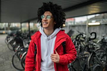 Smiling curly-haired guy renting a bike and looking contented
