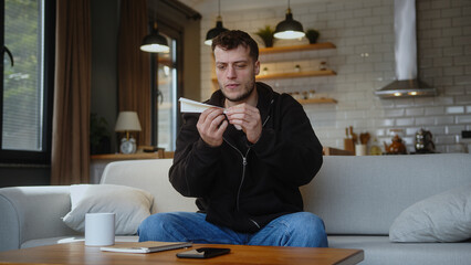 Carefree man sit on couch make paper plane and launch in living room at home