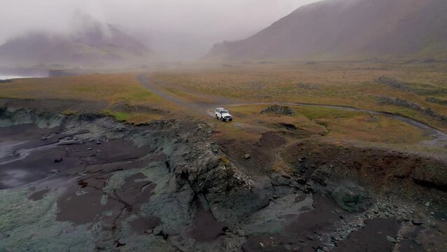 Travel Iceland Offroad 4 Wheel Drive White Car Parked By Epic Coast Ocean Waves Crashing Below. Drone Flies Back Mountains Moody Low Clouds Fog. High Quality 4K Color Corrected.