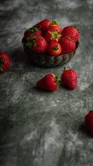 Strawberries in a bowl on a dark rustic background. Selective focus.