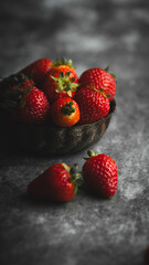 Strawberries in a bowl on a dark rustic background. Selective focus.