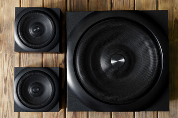 Large cubic subwoofer in a wooden cabinet with metal grille and two audio speakers on a background...