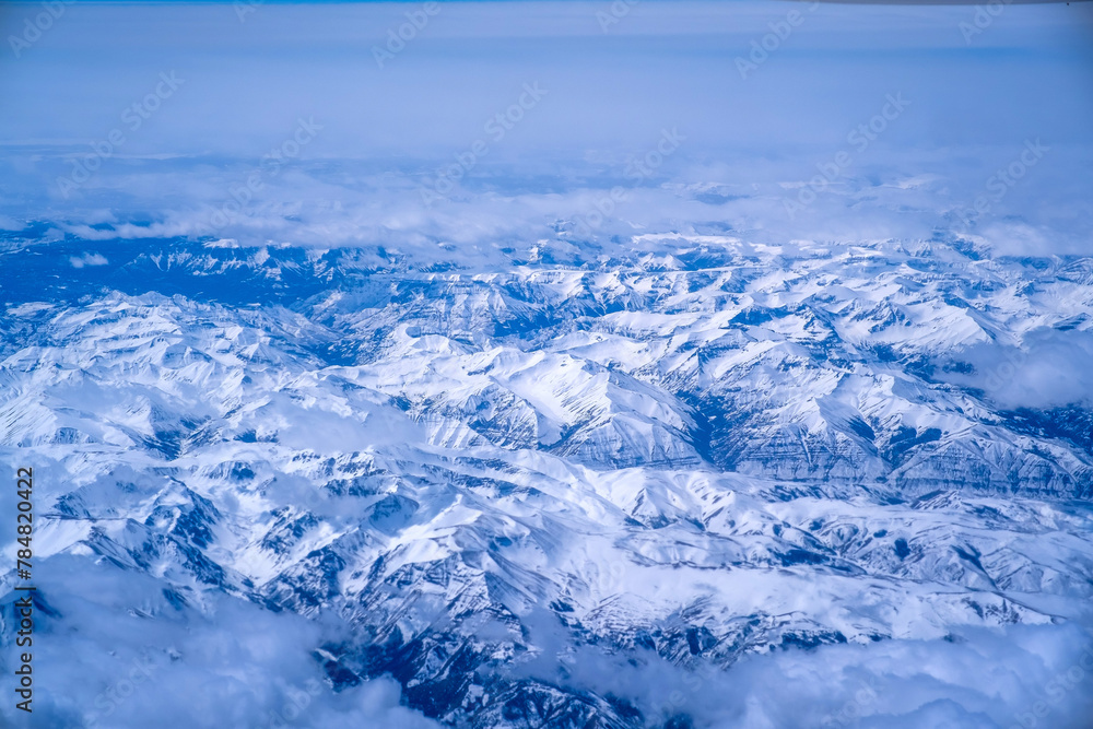 Wall mural top view of mountains with snow and clouds.