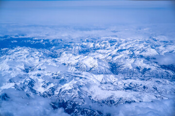 Top view of mountains with snow and clouds.