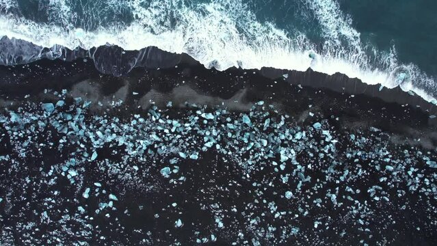 Aerial drone footage of Diamond beach, Iceland. Icebergs washed up on the black beach. Ice diamonds floating in diamond beach in Iceland. Scenic view of an Artic nature ice landscape. Climate change.