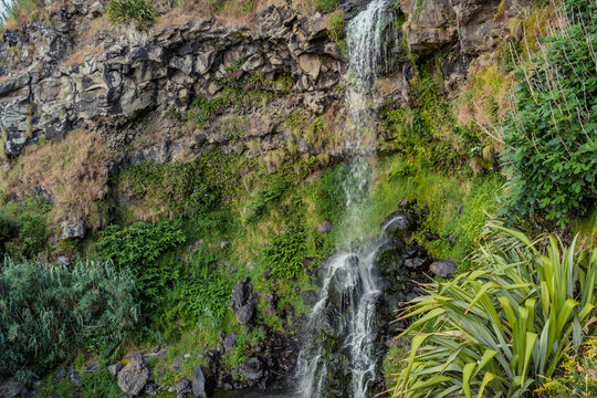 Detail of stream water in motion flowing into cliff and falling into rock, waterfall at Viola beach, São Miguel - Azores PORTUGAL