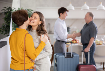 Hospitable friendly young woman warmly greeting and kissing mother-in-law coming for cozy family dinner with set table in background.. © JackF