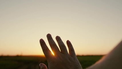 Mans hand reaches for sun, rays of sun break through his fingers. Hand of happy person reaches for...