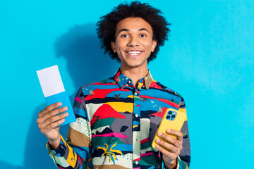 Photo portrait of handsome young guy hold tickets device dressed stylish print garment isolated on blue color background