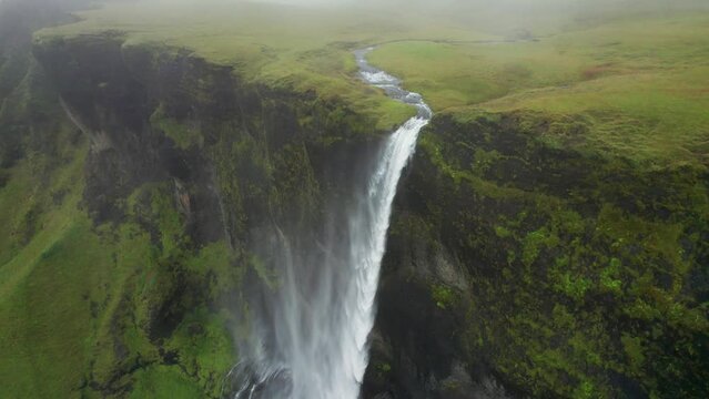 Epic Cinematic Iceland Waterfall Wind Blowing Mist Across Moss Covered Cliffs. Drone Down Waterfalls To Streams Below. High Quality 4K Color Corrected.