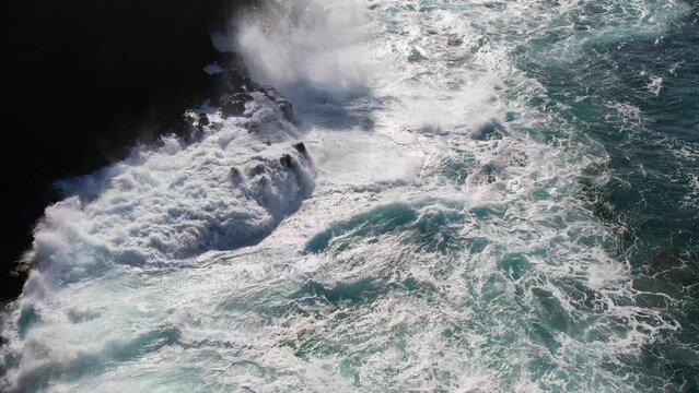 MOLOKAI - 3.19.2024 - Very good aerial footage pulling back from waves crashing on a rocky shore in Molokai, Hawaii in slow motion.