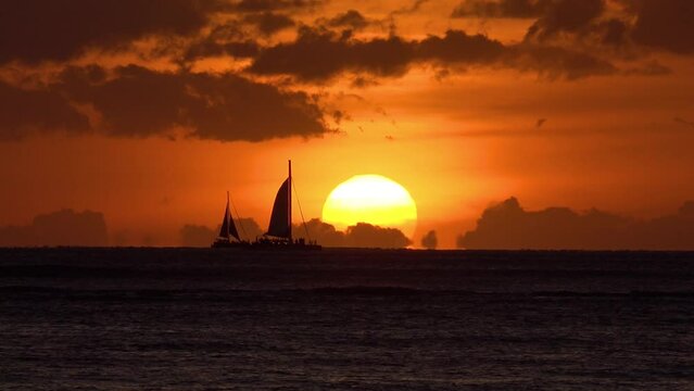 HAWAII - 3.19.2024 - People sail off the coast of Hawaii as the sun sets behind them.