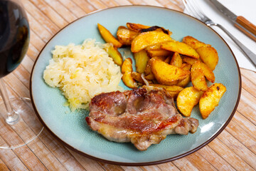 Appetizing roasted pork steak with delicious fried potato slices and stewed cabbage