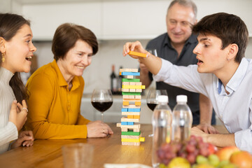 Happy young guy concentrating on removing block from tower while playing jenga, spending free time...