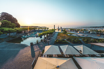 Panoramaansicht des Hafens mit Schiffen, Imperia-Statue und See im warmen Morgenlicht bei Sonnenaufgang. Konstanz, Bodensee, Baden-Württemberg, Deutschland, Europa.