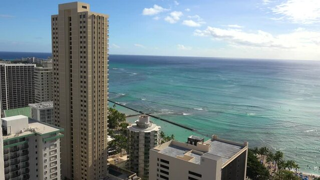 WAIKIKI - 3.19.2024 - Amazing aerial footage of ocean waves lapping towards the shore of Waikiki, Hawaii, where tall buildings stand on the coast.