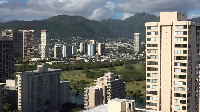 WAIKIKI - 3.19.2024 - Great aerial footage of residential buildings and mountains in the background of Waikiki, Hawaii.