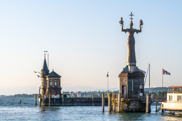 Tourist auf Standup Paddle färht an Leuchtturm und Hafeneinfahrt mit der Konstanzer Fahne vorbei. Konstanz, Bodensee, Baden-Württemberg, Deutschland, Europa.