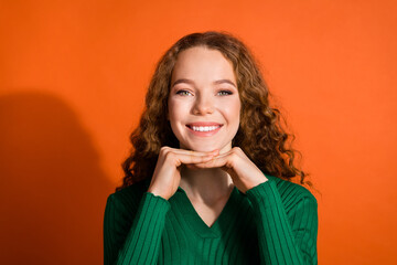 Photo of sweet pretty lady dressed green shirt hands arms chin emtpy space isolated orange color background