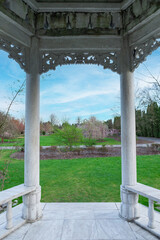 Chinese style white stone gazebo in a lush green park with a park in the background