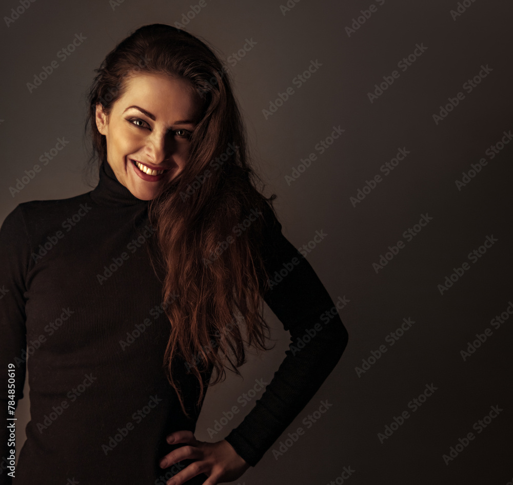 Wall mural Beautiful smiling successful business woman in black clothing looking happy on dark shadow studio background with empty copy space. Closeup