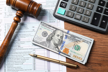 Tax return form, dollar banknotes, gavel, pen and calculator on wooden table, top view