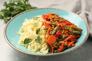 Vegetarian meal. Tasty pasta with vegetables on light grey marble table, closeup