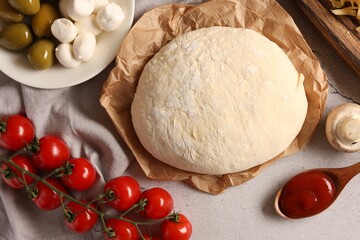 Pizza dough and products on gray textured table, flat lay