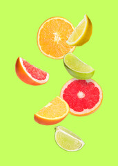 Many different fresh citrus fruits in air on light green background