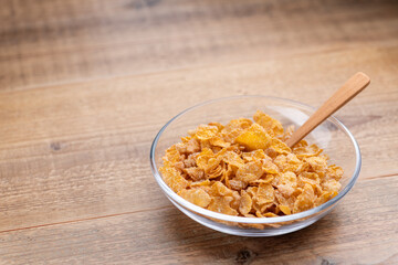 木製のテーブルの上にガラスの器にいれたシリアルと木のスプーン