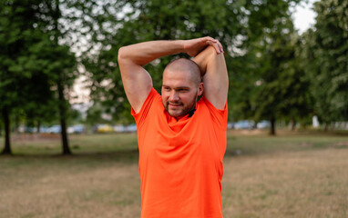 A sporty man is doing stretching exercises before running or workout outdoor in the summer park active healthy lifestyle. 