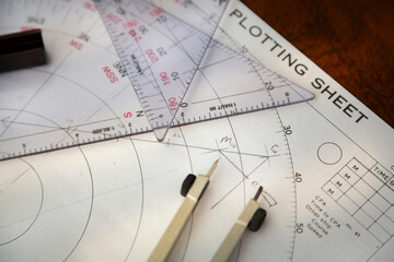 Above image of a navigator's radar plotting chart with a triangler and compass divider and a...