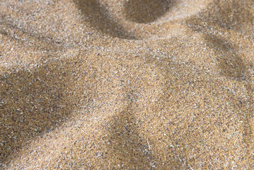 A sandy beach with a lot of sand. The sand is spread out in a way that it looks like a wave