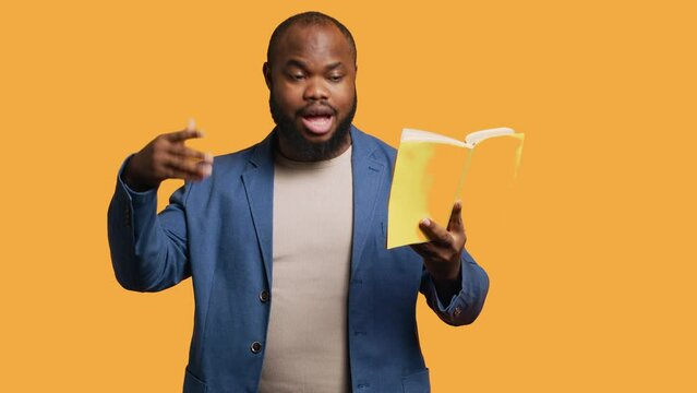 Man reading book aloud, narrating story for audience, doing monologue for theatre play. Person rehearsing using literature novel source material, reciting from pages, studio background, camera A